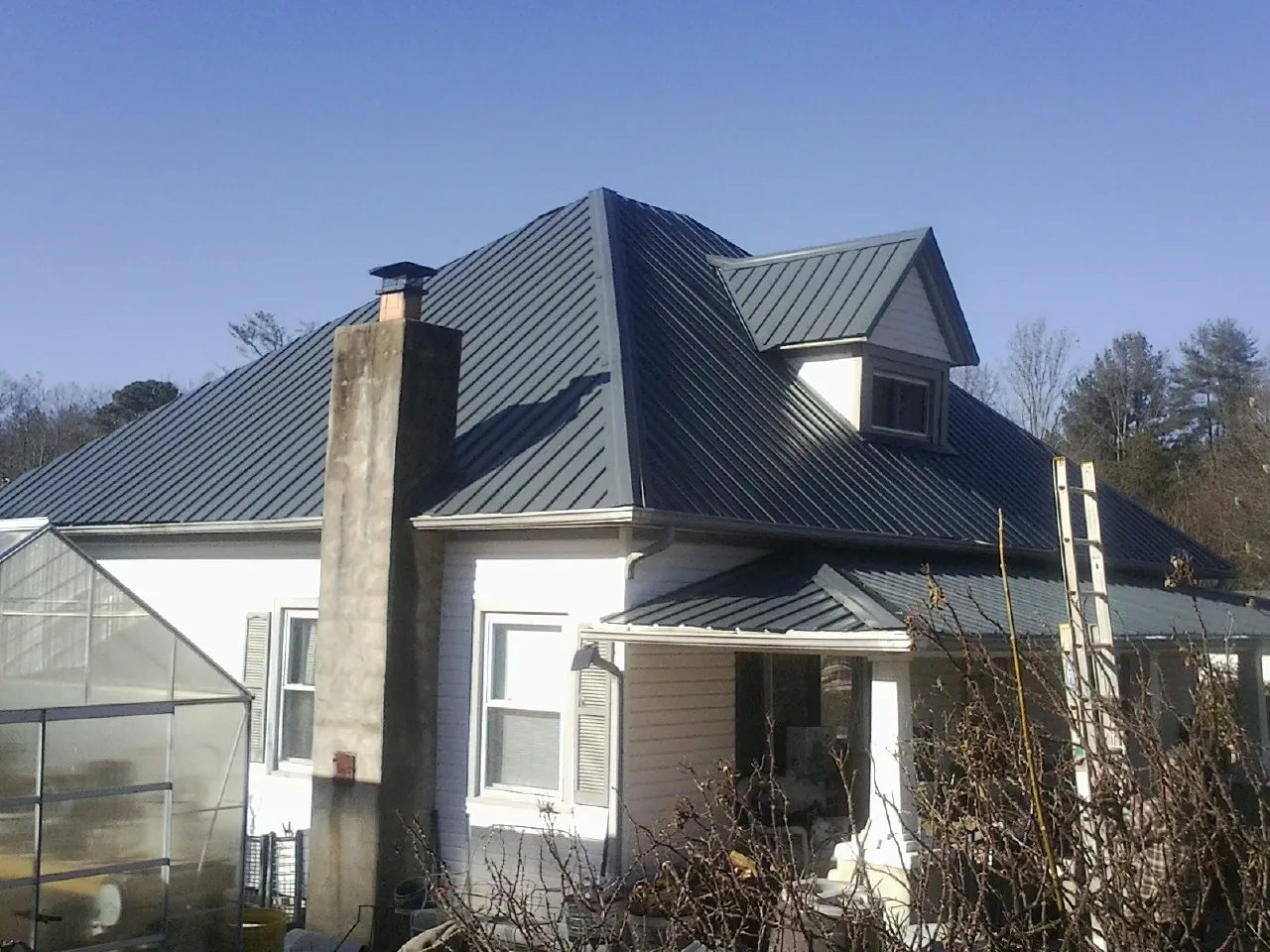 Dark blue standing seam metal roof on a white farmhouse with dormer — Slate & Tile Roof Repair by Roofing Brothers in Stormville