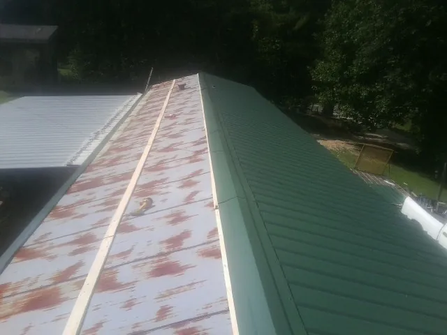 Old rusted panels beside newly installed green metal roofing — Wind Damage Roof Repair by Roofing Brothers in Stormville