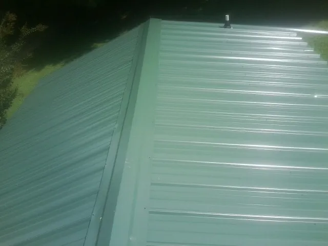 New green metal panels meeting at the ridge of a roof — Flat Roof Repair work by our crew in Stormville
