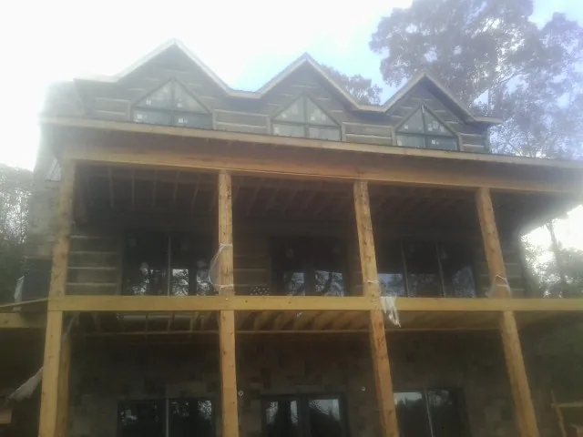 Dormers and porch framing on a large log home under construction — Roof Coating work by our crew in Stormville