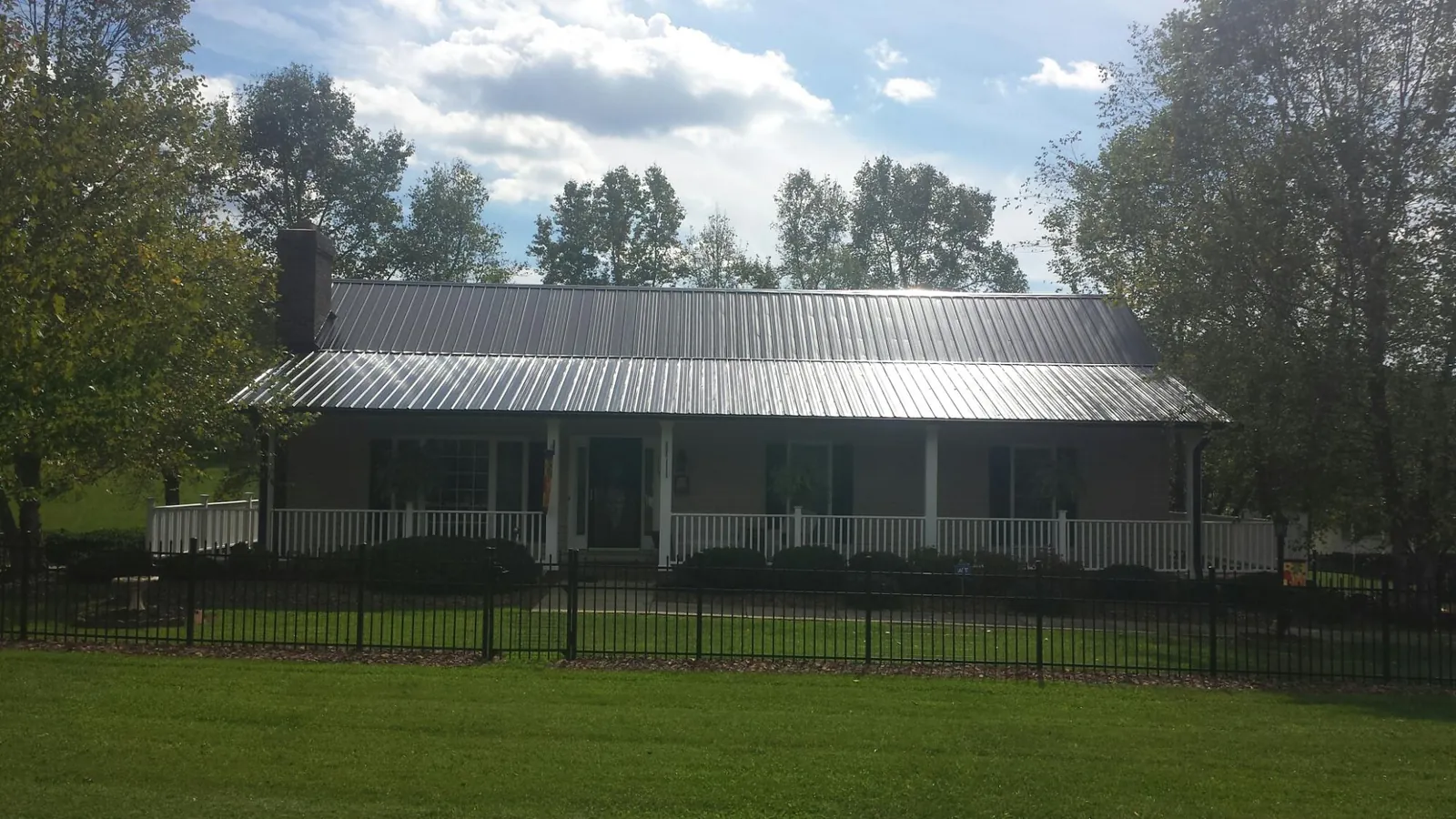 Gray metal roof on a brick ranch with a full width front porch — Gutter Guard Installation work by our crew in Stormville