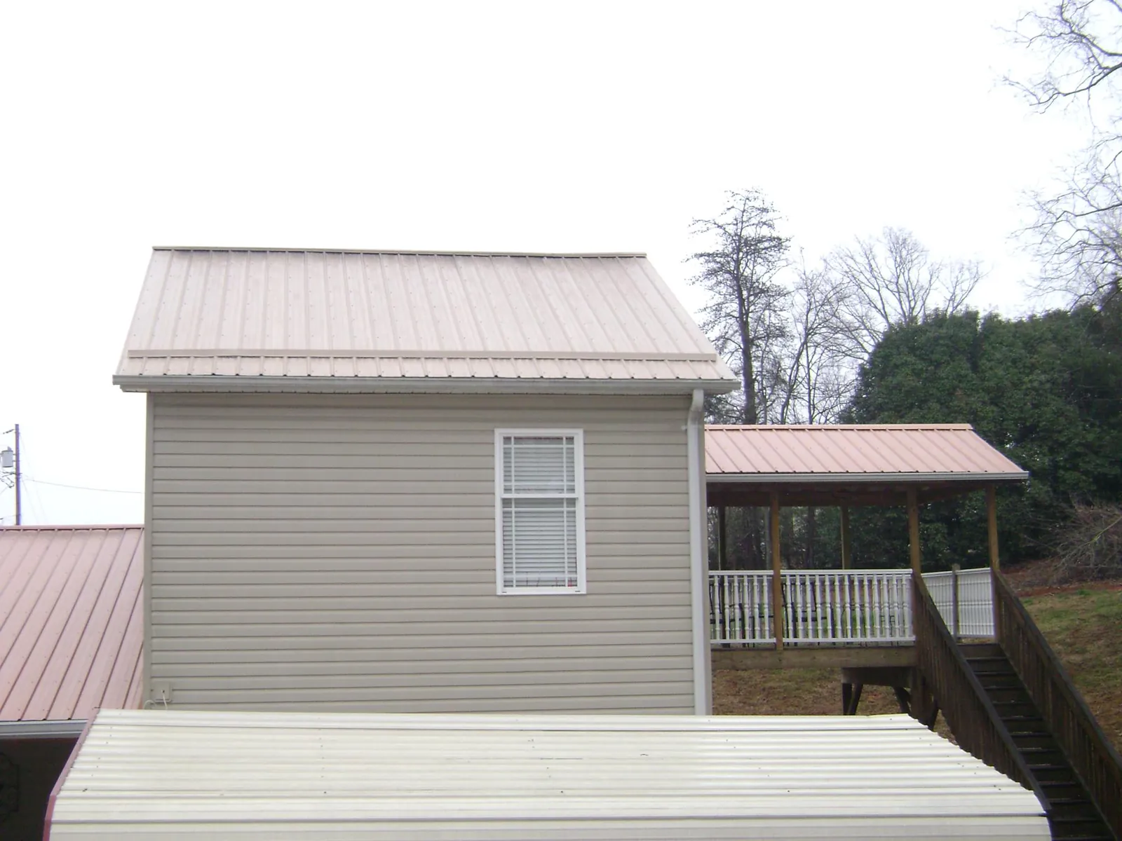 Tan metal roofs on a two story addition and attached porch, from a Roof Replacement job in Stormville