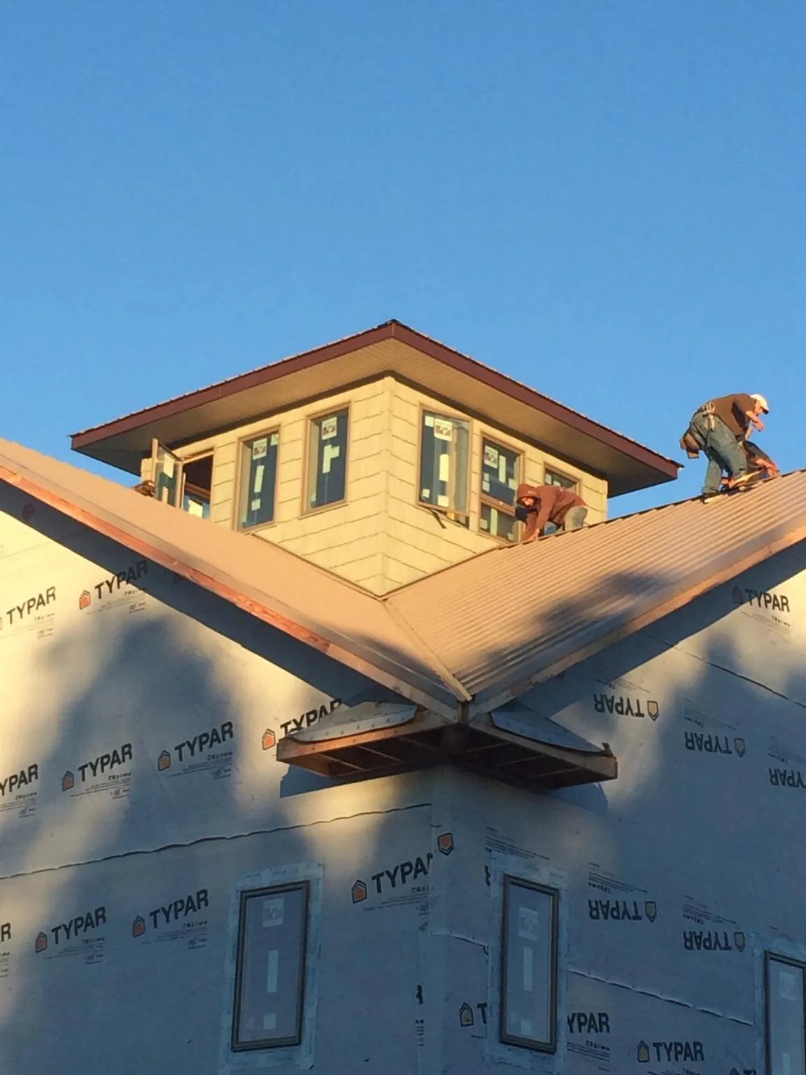 Roofers working around a rooftop cupola on a new metal roof at sunset — Roof Waterproofing in Stormville by Roofing Brothers
